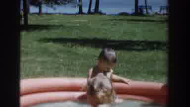 Wisconsin USA (1953): Two Children In A Small Swimming Pool And A Child On A Swing