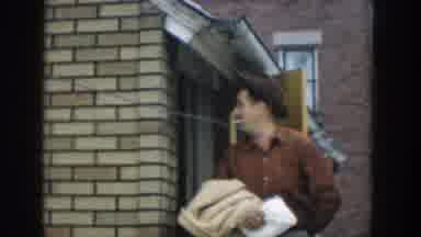 Michigan USA (1957): Man Smoking Cigarette Holding Door For Woman Walking Out The
