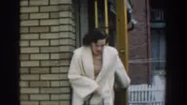 Michigan USA (1957): Woman In White Jacket Leaves Her House And Smiles Shyly