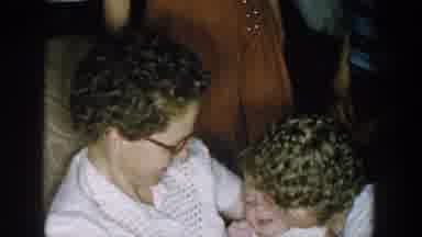 Michigan USA (1957): Two Old Ladies Sitting Down Fawning And Kissing A Baby