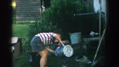 Michigan USA (1957): A Boy Appears To Be Imitating An Adults Behavior Tending To