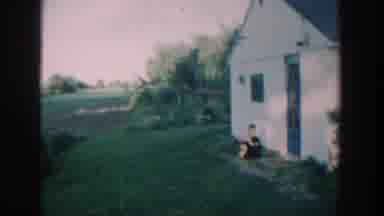 Michigan USA (1957): A Little Boy Petting His Black Dog Out By The Garage