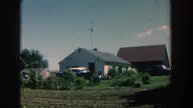 Michigan USA (1957): Outside Of A House In Front Of A Plow Field A Man Rakes And A