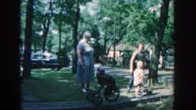 Wisconsin USA (1957): A Woman Supervises Children Playing In The Front Yard Of A
