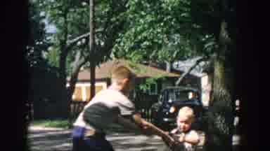 Wisconsin USA (1957): Teenage Girl In Front Of House On Aboriginal Street Picks Up