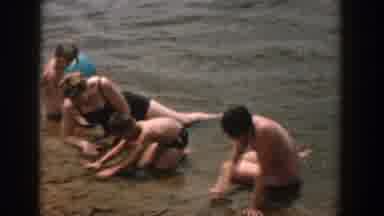 Wisconsin USA (1957): People On A Beach Sitting On The Sand At Waters Edge