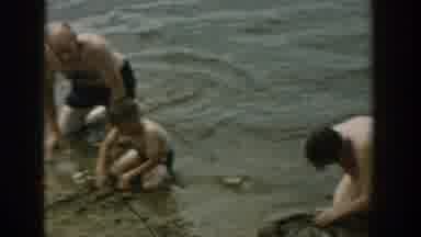 Wisconsin USA (1957): Two Men And A Boy Is Playing In The Sea With Sand