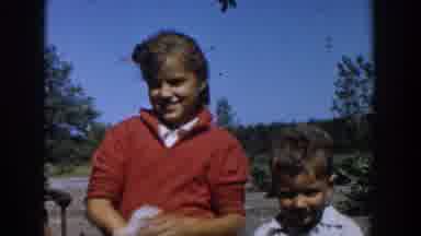 Michigan USA (1958): Little Boy Standing Next To Older Sister Watching Grandfather