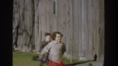 Michigan USA (1958): A Brother And Sister Are Chasing Each Other Down A Street