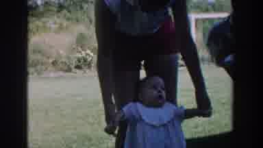 Michigan USA (1958): Standing Baby Laughing With Both Parent Outside On A Field