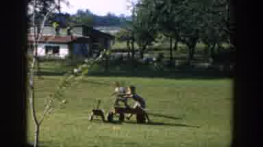 Michigan USA (1958): Three Boys Are Playing In Their Wagons In A Grass Field