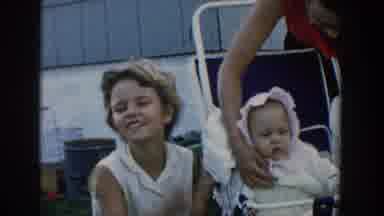 Michigan USA (1958): A Mother Taking Care Of Her Youngest Child, While The Other