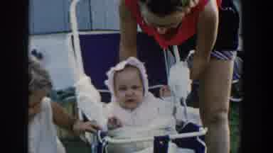Michigan USA (1958): Woman Adjusting Fussy Baby In A Stroller As A Small Girl