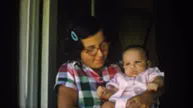 Michigan USA (1958): Woman Holding Baby, Child Riding Around Car With A Bike
