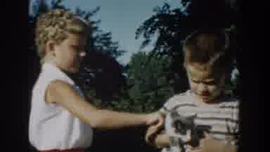 Michigan USA (1958): Girl And Boy Holds Cat,Woman Holds Baby,In Yard On Sunny Day