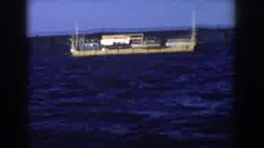 Wisconsin USA (1958): Long Boat Drifting Across Body Of Water On Clear Sunny Day