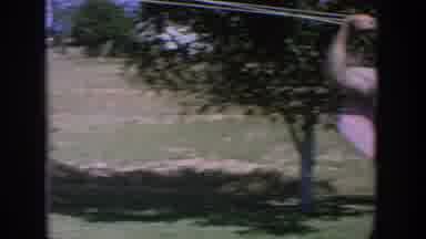 Wisconsin USA (1964): A Woman Sits In The Sun As Another Man And Woman Stand Next