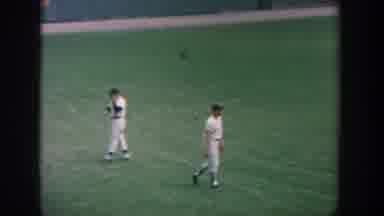New York USA (1964): Two Baseball Players Running Across Green Field Throwing