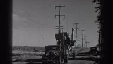 California USA-1936: Man On Loaded Flatbed Trailer Being Pulled By Classic Car