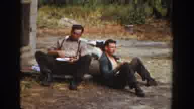 California USA (1936): Men Sitting Sunny Outside Ground Resting Eating Scraping