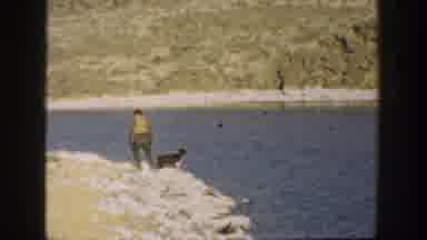 California USA (1936): Young Boy Playing With Black And White Dog At The Lake