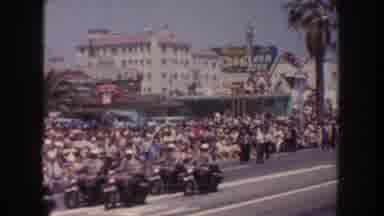 California USA (1952): Police In Motorcycles Ride Down Street While Crowd Of