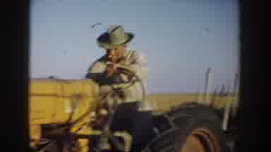 South Dakota USA (1953): Man Starting Tractor With Hay Filled Trailer On Clear