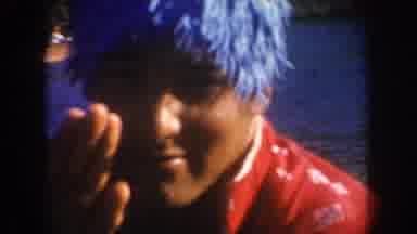 South Dakota USA (1954): Man Waving Wearing Blue Wig With Ocean On Background