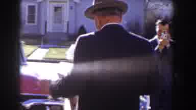 Idaho USA (1955): A Man Walking Out Of A House Towards Car While People Watch Him