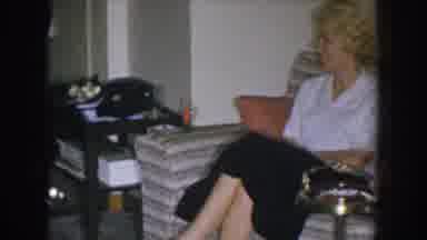 Nebraska USA (1955): A Smiling Woman Sits On A Couch Next To A Man Drinking A Beer