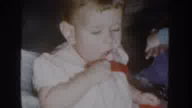 Nebraska USA (1955): Baby Wearing Red And White Shirt Sitting On Floor Eating