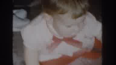 Nebraska USA (1955): A Baby Sitting On The Floor Reaches For A White Object And