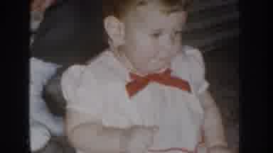 Nebraska USA-1955: Pretty Toddler in White Dress with Red Bow Wiggling Hands