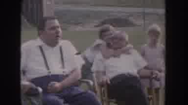 Nebraska USA (1955): Adults Sitting Outside When A Young Child Comes And Hugs One