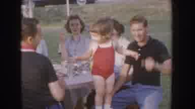 Nebraska USA (1955): Baby Standing On Picnic Chair In Bathing Suite Putting Arms