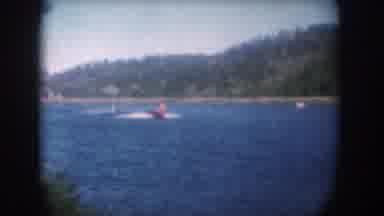 South Dakota USA (1956): Red Speed Boat Towing Two Water-Skiers On A Blue Lake