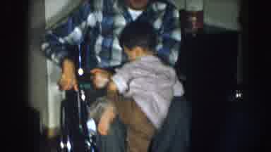 Nebraska USA (1957): Boy Climbs Up Father's Lap To Kiss Him In Wheelchair