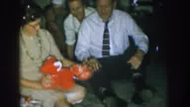 Nebraska USA (1957): People Looking At A Woman Playing With A Red Toy