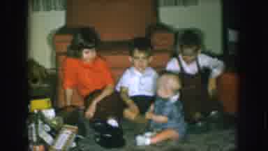 Nebraska USA (1957): Kids Playing In A Living Room In Front Of An Armchair Sitting