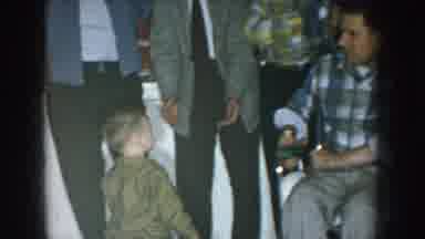 Nebraska USA (1957): Men Standing By Window Hold Small Boy At Holiday Party