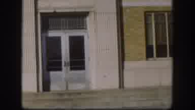 Kansas USA (1958): A Man Walking Out Of A Building, Taking Off His Hat And
