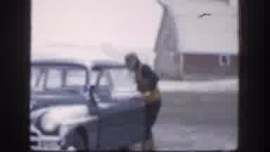 Kansas USA-1958: Frozen Man Placing Jacket Into Classic Car In Snowy Rural Scene