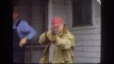 Kansas USA (1958): Man Wearing Red Hat Points Rifle At Camera Walks To Blue Car