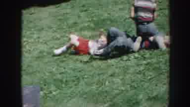 Nebraska USA (1958): Three Small Children Roughhousing Outside In The Grass