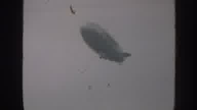 Nebraska USA (1958): Blimp Soars Thru Grey Sky Over Power Lines Free From Birds Or