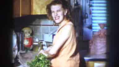 Nebraska USA (1958): Smiling Woman In Kitchen Cuts Celery Stalks To Feed Horse
