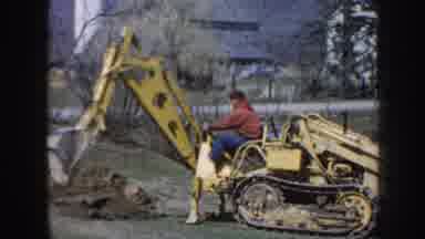 Nebraska USA (1958): Young Chubby Child Wearing Coat To Man Tractor Digging Hole