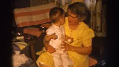 Nebraska USA (1959): Mother Sitting In Her Living Room With One Of Her Kids On Her