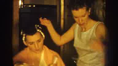 Nebraska USA (1959): A Woman Curling Another Woman Hair In A Close Quarters House