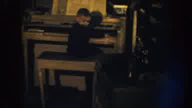 Nebraska USA (1959): Boy Playing On Organ Baby Drinking From Bottle Woman Covering